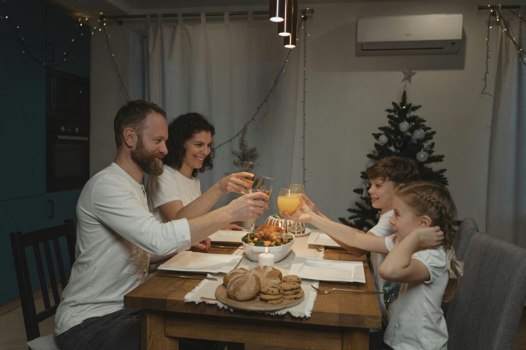 A joyful family toasting at a festive dinner table with festive decor indoors.